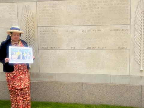 Congresswoman Amata with historic photo of Henry Saaga at the Wall in Normandy where his name is engraved